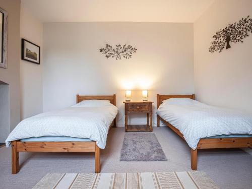 Stocksfield的住宿－The Cottage，一间设有两张床和一张带两盏灯的桌子的房间