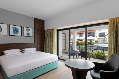 1 dormitorio con cama, mesa y balcón en Fairfield by Marriott Goa Benaulim en Benaulim