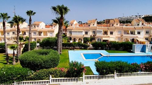 un gran complejo de apartamentos con piscina y palmeras en Villa del Sol, en Gran Alacant