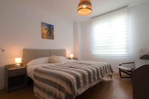 a bedroom with a bed with a striped blanket and a window at THE SEA VIEW CALACEITE in Torrox Costa
