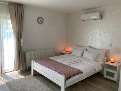 a bedroom with a white bed and two lamps on tables at Fruška Gora Guesthouse in Irig