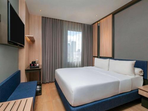 1 dormitorio con 1 cama blanca grande y TV en ibis Surabaya Tidar, en Surabaya