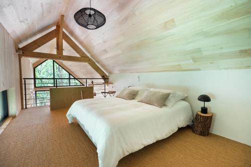 een slaapkamer met een groot wit bed op een zolder bij Wabi sabi lodge&spa in Turenne