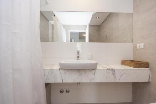 Baño blanco con lavabo y espejo en Libertador Complete Suite en Buenos Aires