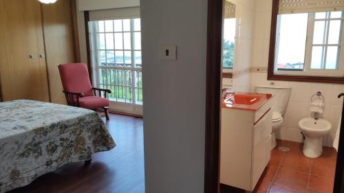 a room with a bed and a bathroom with a toilet at Os piñeiros vacacional in Moaña