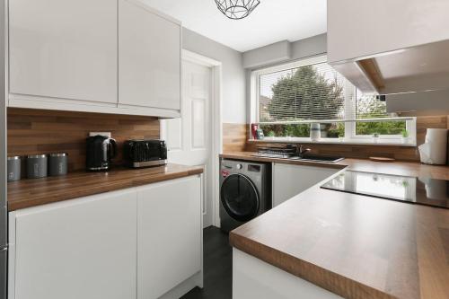 a kitchen with white cabinets and a washer and dryer at Superb 3 bed house, homely comforts close to supermarkets, with private parking on gated premise in Sheffield