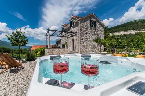 a hot tub with two wine glasses in it at Villa Le Adria - Private HotTub - Free Beach Parking in Kozica