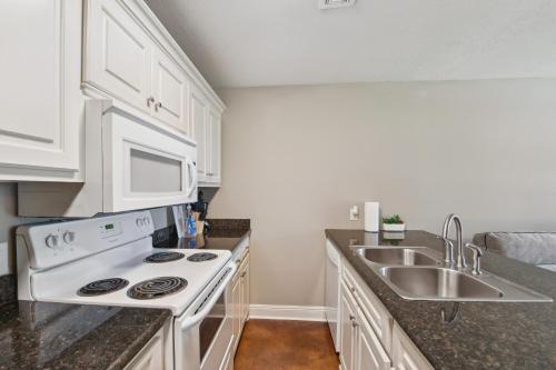 a kitchen with a white stove top oven next to a sink at Lovely Lake Charles Duplex in Central Location! in Lake Charles