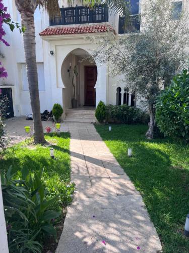 une passerelle devant une maison arborée dans l'établissement Les jardins Malabata, à Tanger