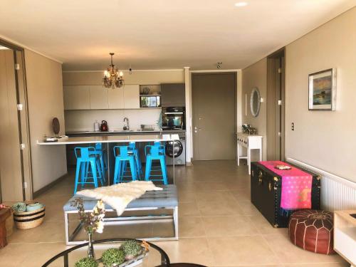 a living room with a kitchen and blue stools at Departamento Banus Marbella piso 1 in Maitencillo