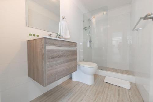 a white bathroom with a toilet and a shower at Boutique Apartments Panama Atlapa in Panama City
