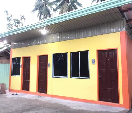 un pequeño edificio amarillo y naranja con tres puertas en Budget-StudioRoom-Panabo-Homestay en Panabo