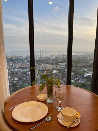 a table with plates and glasses and a vase on it at Verdela Pollux Meisterstadt Batam apartement in Batam Center