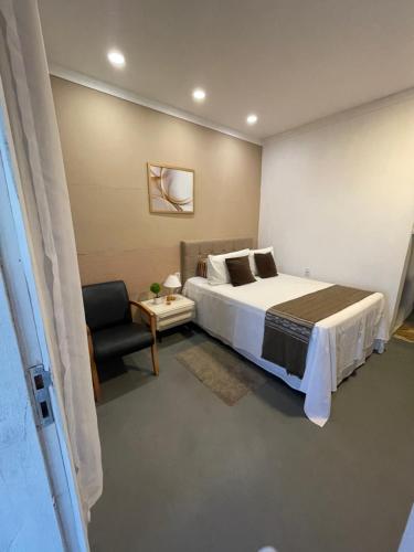 um quarto com uma cama grande e uma cadeira em Pousada Alto da Serra em Serra de São Bento