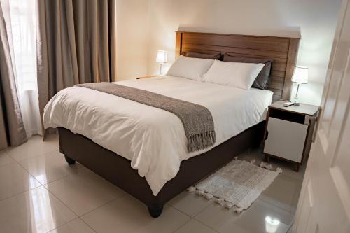 a bedroom with a large bed with a wooden headboard at Hi-Life Villa in Gaborone