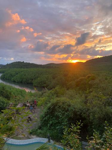 a sunset over a river with people sitting on a bench at Sanctuaria Treehouses Busuanga in Busuanga