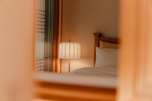 a bedroom with a bed with a lamp and a mirror at Gyeongju Hanok Sohwa in Gyeongju