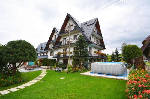 a house with a swimming pool in the yard at Apartamenty Willa Anna in Poronin