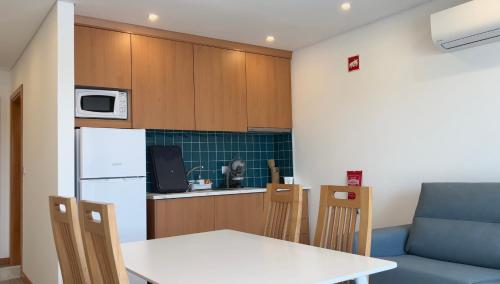 a kitchen with a white table and chairs and a couch at School Motorhome Park in Óvoa