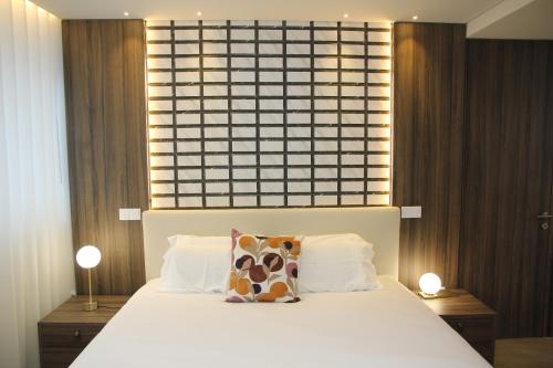 a bedroom with a large white bed with two lamps at BrandApartments in Porto