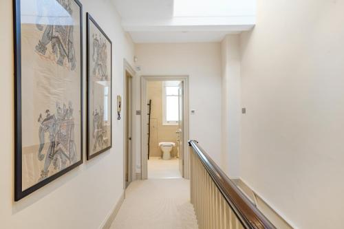 a hallway with paintings on the walls and a stairway at Spacious and Modern 4 beds home in Kensington in London
