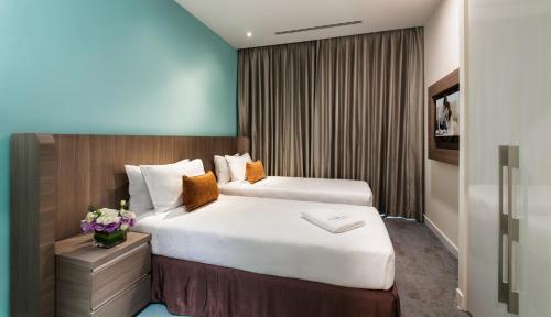 a hotel room with two beds and flowers in it at Citadines DPulze Cyberjaya in Cyberjaya