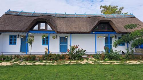 a large white house with a thatched roof at Pensiunea Casa Golovita in Jurilovca