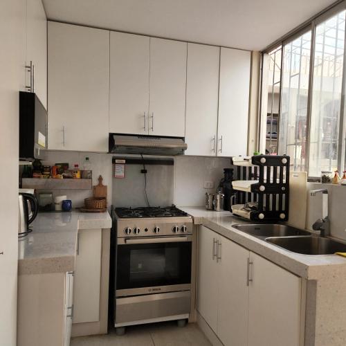 a kitchen with white cabinets and a stove and a sink at Casa Cultura in Lima