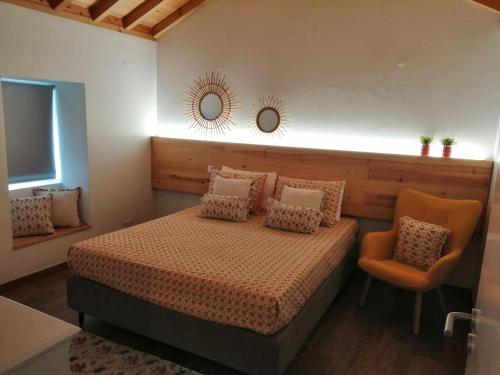 a bedroom with a bed and a chair and a mirror at Ti Chôa - Casa da Mata in Angra do Heroísmo