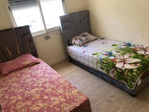 una camera con due letti in una stanza con due finestre di Superbe appartement en résidence avec piscine a Skhirat
