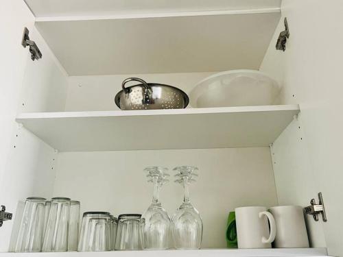 a white shelf with glass bottles and cups on it at 2 Bedroom, Clutter free in Pretoria