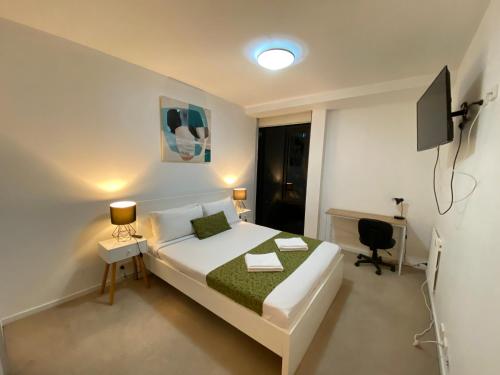 a bedroom with a bed and a desk and a television at AKOM AT Docklands in Melbourne