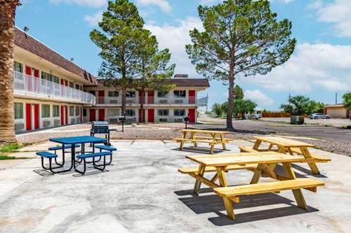 a group of picnic tables in front of a building at Rodeo Inn in Pecos