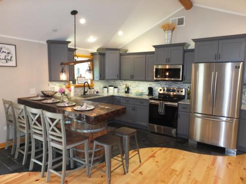 a kitchen with gray cabinets and a kitchen island with bar stools at New! La Maison Malabar - Gorgeous Luxury Cabin! in South Haven