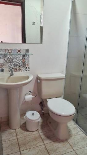 a bathroom with a toilet and a sink at Casa Enorme em condominio, 4 suites, piscina com cascata, cozinha gourmet com churrasueira e fundo com pier no rio para práticas aquaticas in Bertioga
