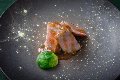 a piece of meat and a green leaf on a plate at Matsumoto Hotel Kagetsu in Matsumoto