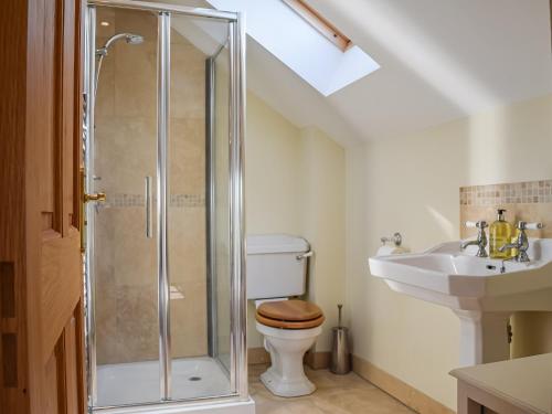 a bathroom with a shower and a toilet and a sink at The Stables in Whissendine