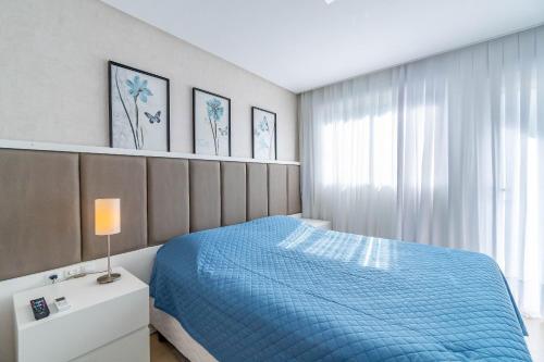 a bedroom with a blue bed and a window at Apartamento de Luxo com Jacuzzi Privativa - Boulevard Bombinhas in Bombinhas