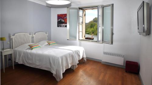 a white bedroom with a bed and a window at Auberge des Platanes in La Roque-Gageac