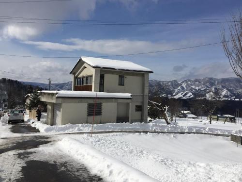 uma casa com neve no chão em frente dela em NIKONOS III em Nozawa Onsen