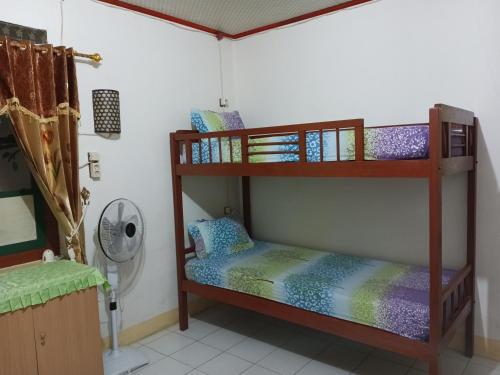 two bunk beds in a room with a fan at MJR Ticketing Guest House in Ruteng