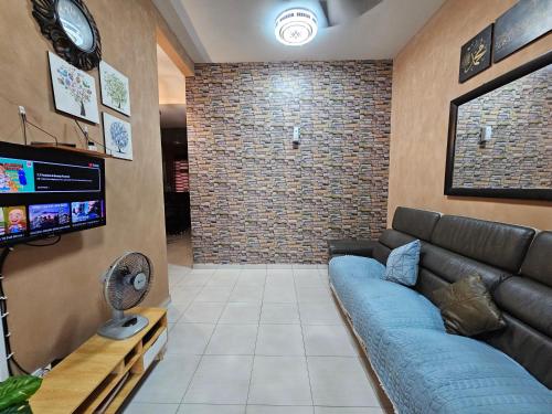 ein Wohnzimmer mit einem Sofa und einem TV in der Unterkunft Lyn Melaka Homestay in Malakka