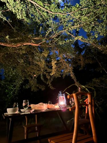 a table with wine glasses on it under a tree at Ranakeliya Lodge - Yala in Yala