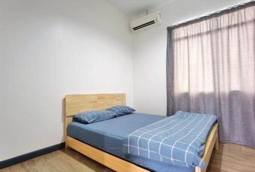 a bedroom with a bed with a blue comforter and a window at 3 mins to Garden City & Kubota Jln Apas Homestay in Tawau
