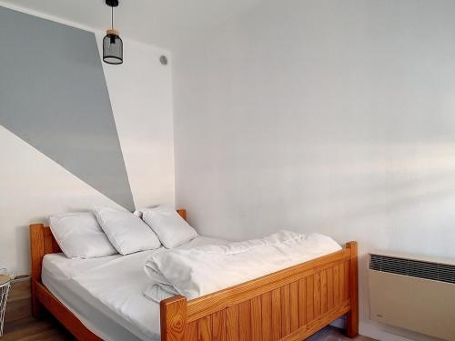 un lit avec des draps blancs et des oreillers dans une chambre dans l'établissement Charmant T2 rénové à 300m de la plage avec parking privé à Courseulles-sur-Mer - FR-1-746-3, à Courseulles-sur-Mer