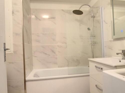 une salle de bain blanche avec une douche et un lavabo dans l'établissement Charmant T2 rénové à 300m de la plage avec parking privé à Courseulles-sur-Mer - FR-1-746-3, à Courseulles-sur-Mer