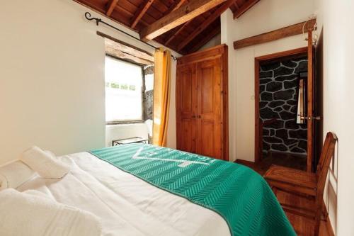 a bedroom with a bed with a green blanket on it at holiday home, Praínha de Baixo, Pico, Azores in Prainha de Baixo