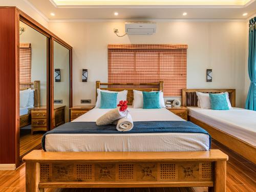a bedroom with two beds and a mirror at Maison D'Aaryan in Anse aux Pins