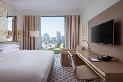 a hotel room with a bed and a desk with a television at Baku Marriott Hotel Boulevard in Baku