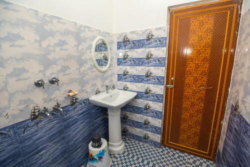 ein Badezimmer mit einem Waschbecken und einer Dusche mit blauen Fliesen in der Unterkunft Jungle Eco Mansion in Kāziranga